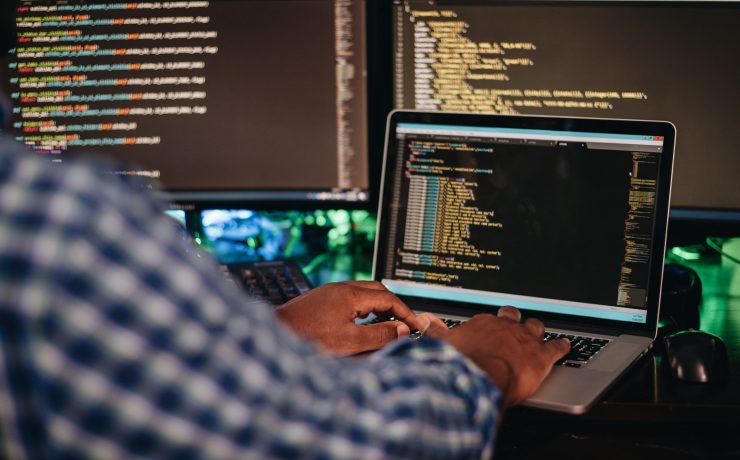 African American man sitting at a computer developing software through coding