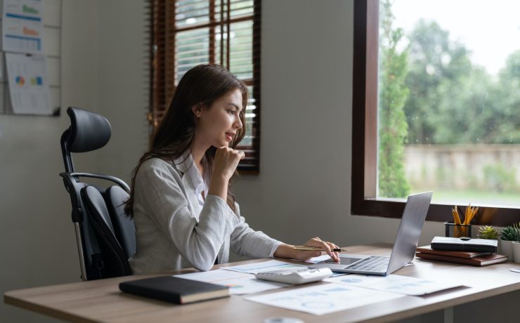Woman accountant using calculator and computer in office, finance and accounting concept.