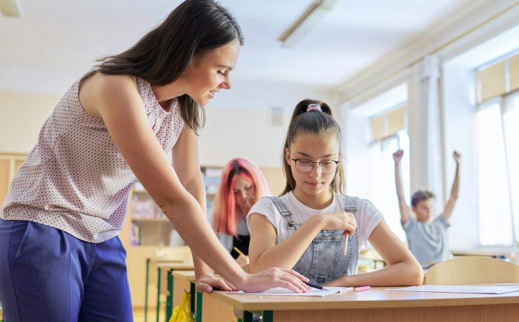 Young woman teacher teaches lesson in class of teenage children